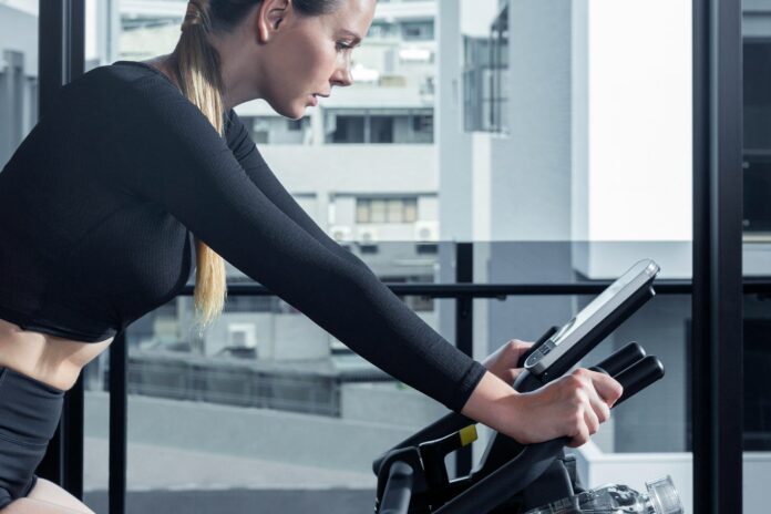 Photo by Intenza Fitness a woman on a stationary bike using a tablet