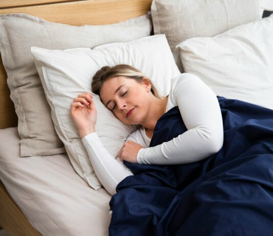 수면의 질을 높이는 5가지 실질적인 생활 습관 a woman sleeping on a bed with a blue blanket