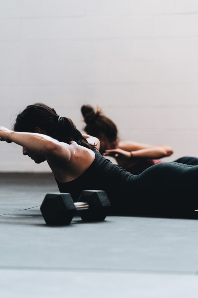 Photo by LOGAN WEAVER | @LGNWVR woman in black tank top and black leggings lying on black floor