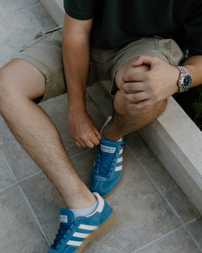 A man sitting on a ledge tying his shoes