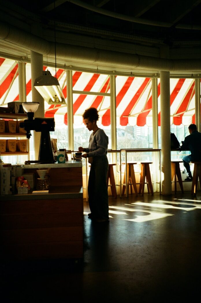 Barista working behind counter in sunlit cafe